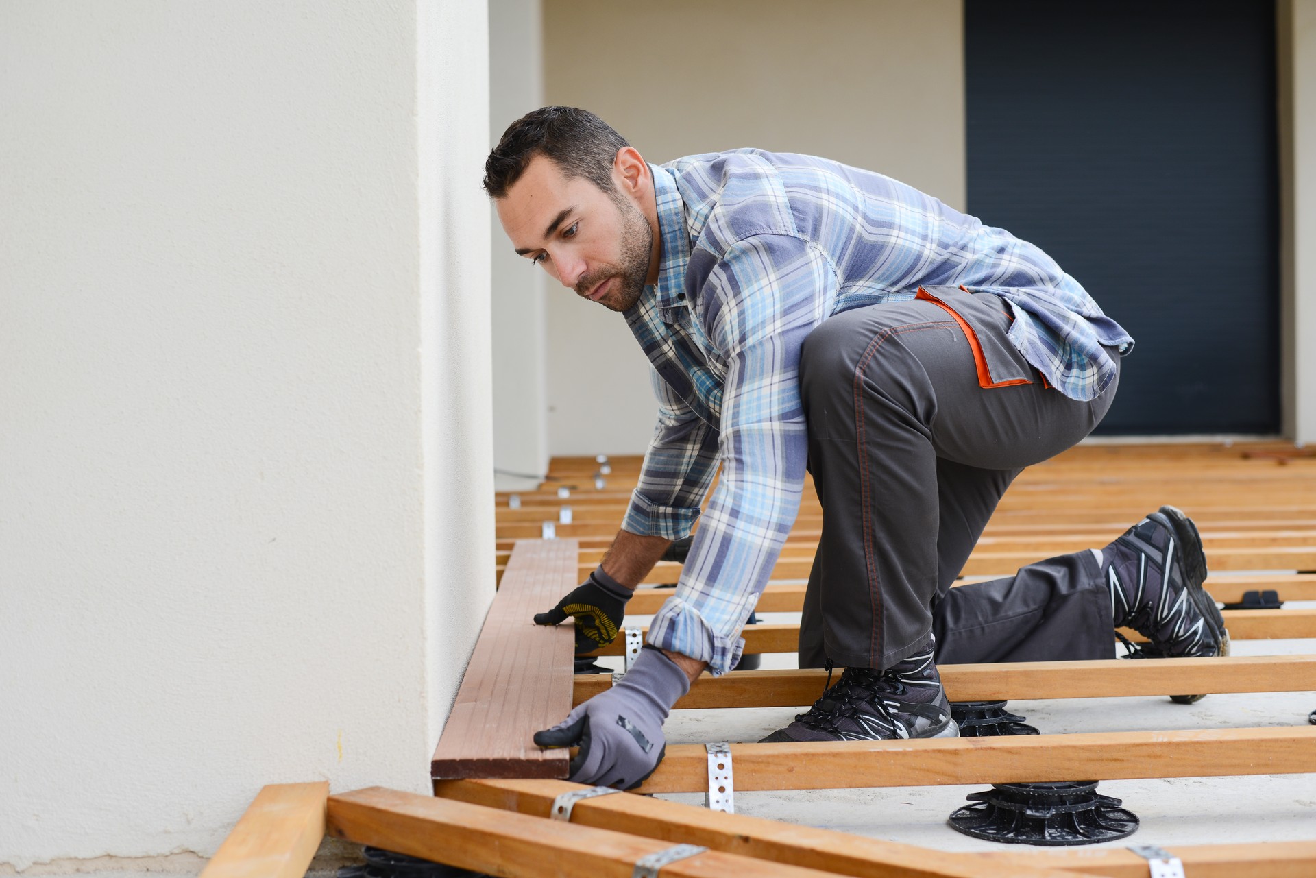 handsome young man carpenter installing a wood floor outdoor terrace in new house construction site